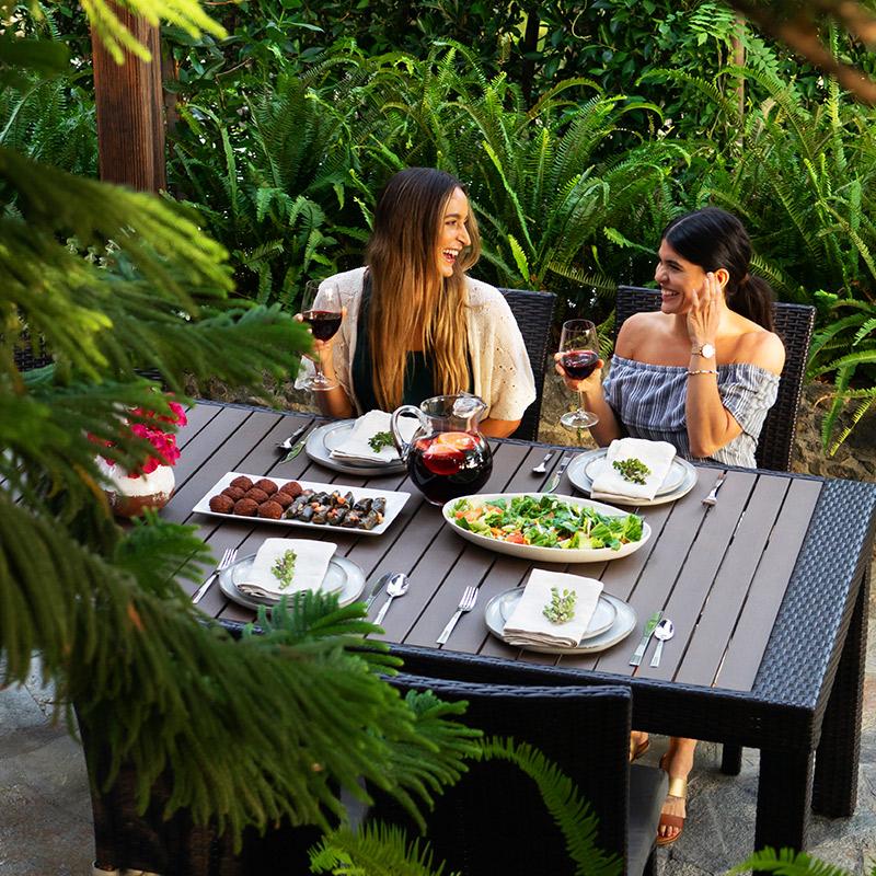 women conversing at outdoor table with food and drink
